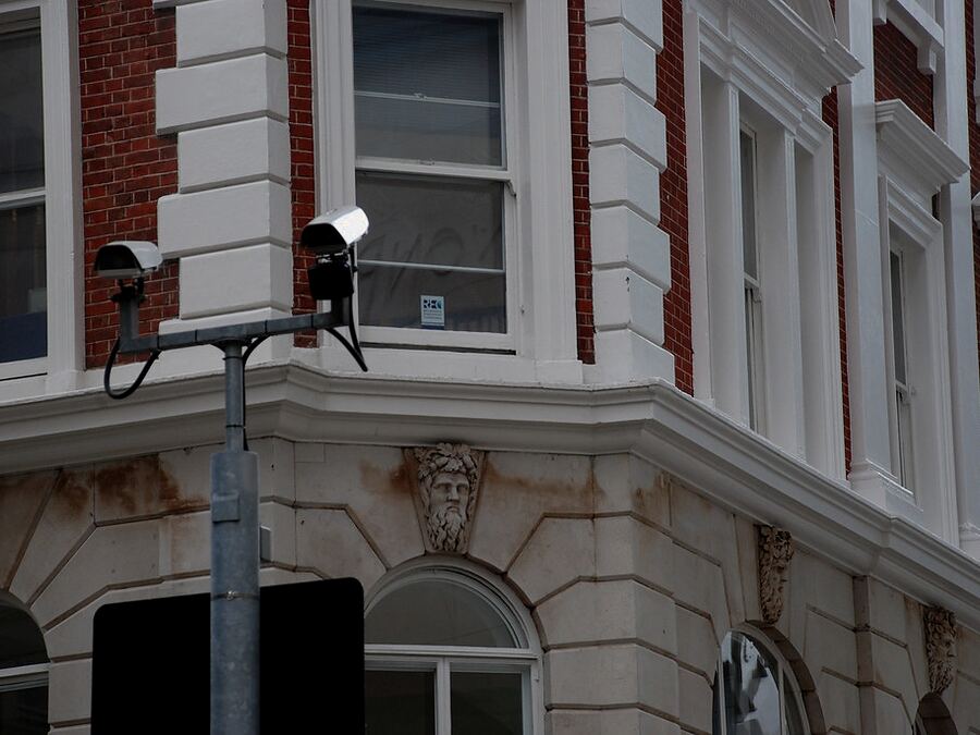 Two CCTV cameras mounted together on a pole outside an older Durban building